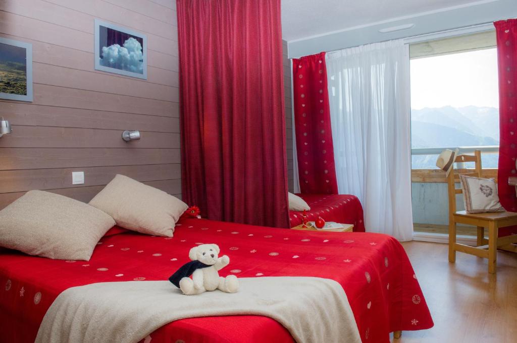 a teddy bear sitting on a bed in a bedroom at Village Vacances Le Tarbesou in Ax-les-Thermes