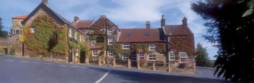 ein großes Backsteingebäude mit einem Zaun vor einer Straße in der Unterkunft Duke Of Wellington Inn in Danby