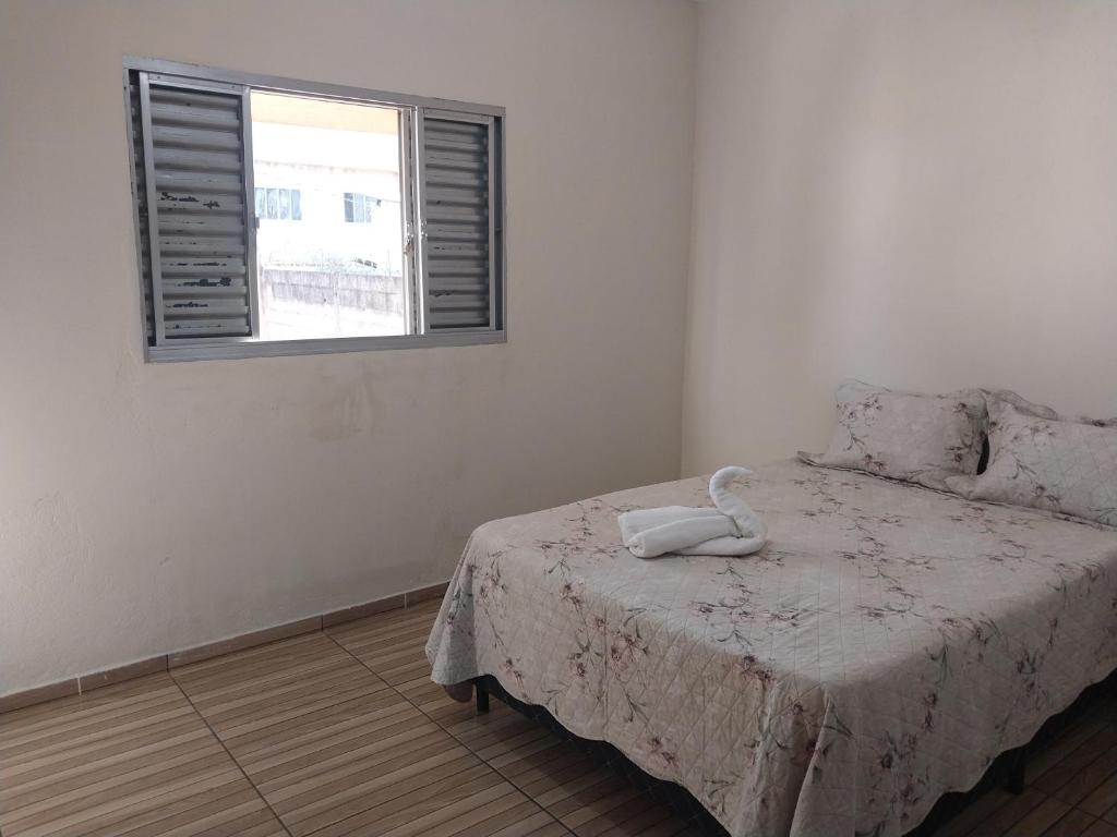 a white bedroom with a bed with a window at Casa para Temporada in São Thomé das Letras