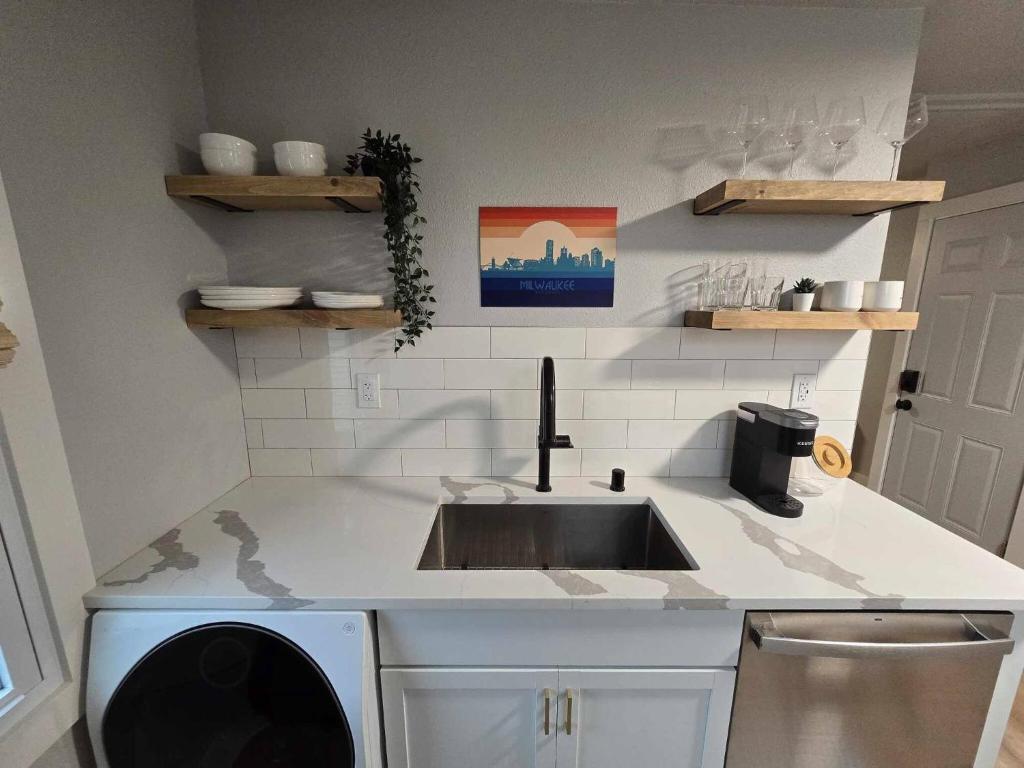 a kitchen counter with a sink and a dishwasher at Stylish Modern Studio in Vibrant Walker's Point in Milwaukee