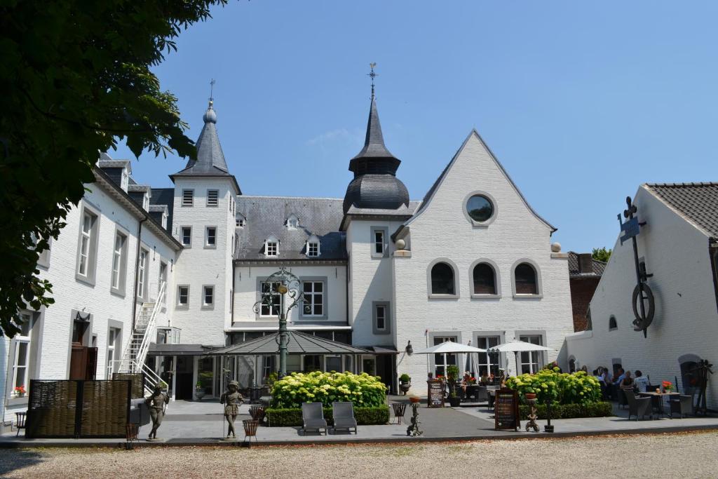 un grande edificio bianco con persone che camminano davanti di Hotel Kasteel Doenrade a Doenrade