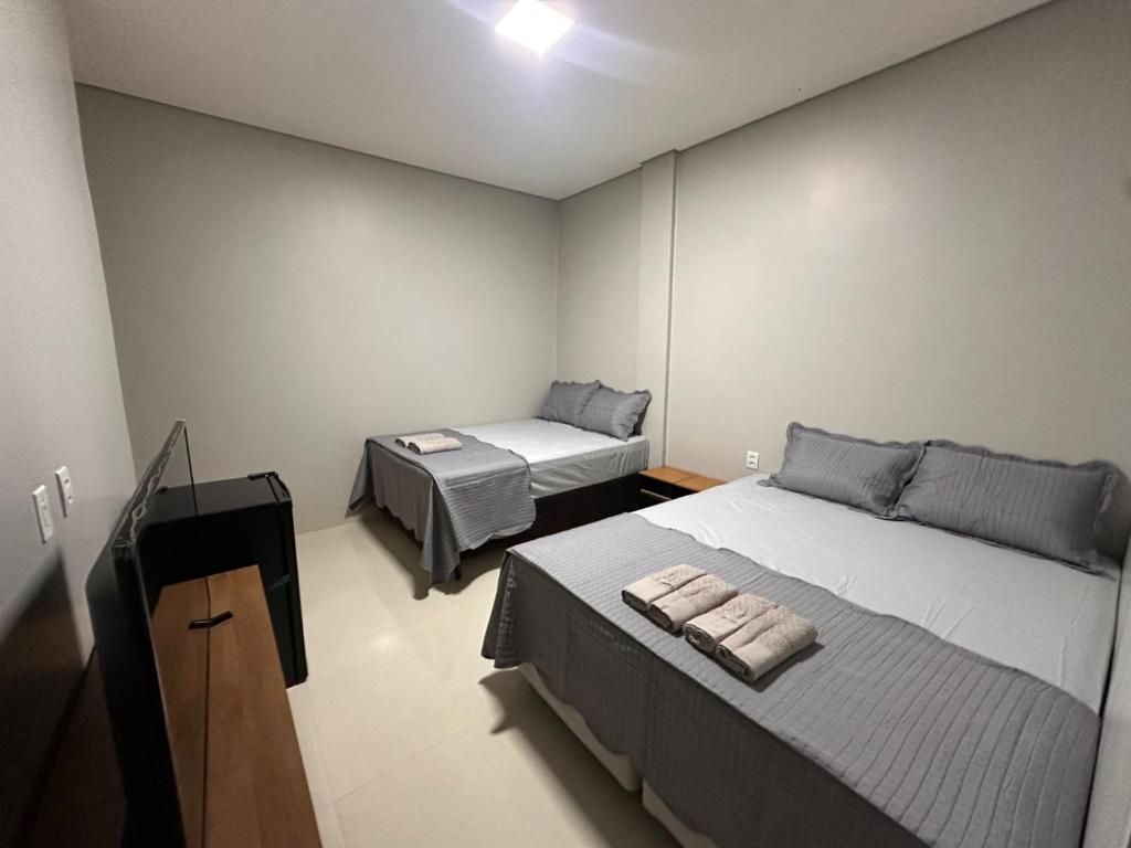 a bedroom with two beds and a television in it at Hotel Araguaia Exclusive in Aruanã