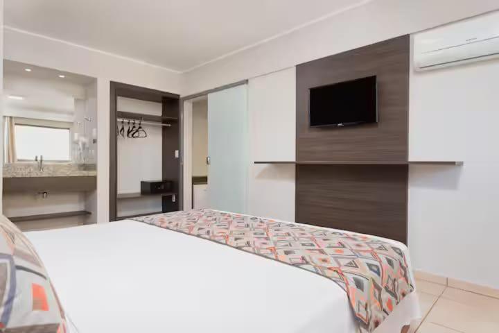 a white room with a bed and a tv at Wyndhan Royal Hotel Resort Olimpia in Olímpia