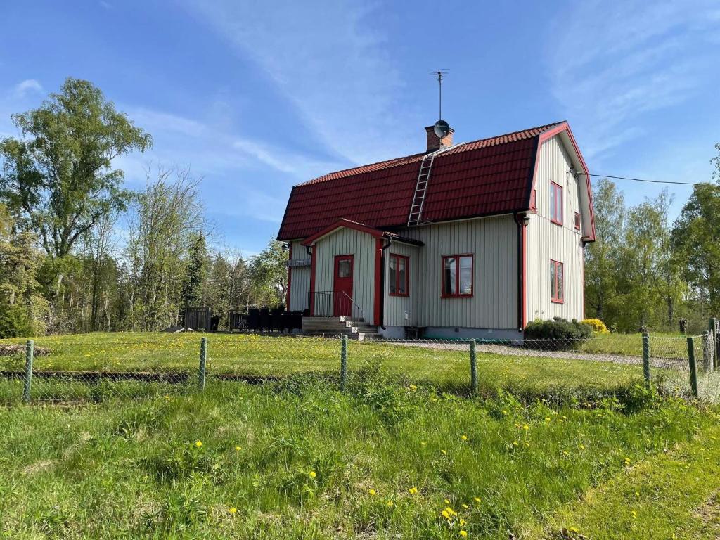 a small house with a red roof in a field at Secluded House with Garden and Lakes in Kristdala