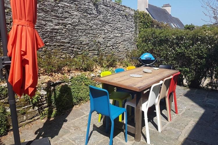 une table en bois avec des chaises et un parasol dans l'établissement Holiday Home in Locquirec near Sandy Beach, cleaning included, à Locquirec