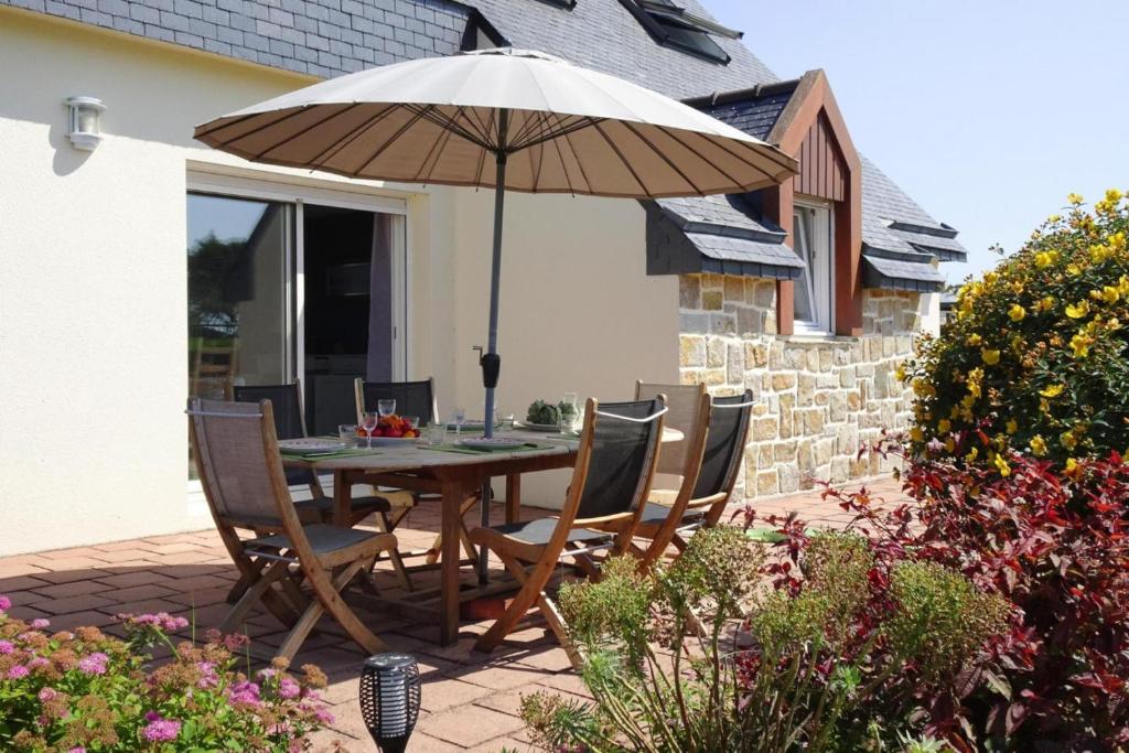 une table et des chaises avec un parasol sur une terrasse dans l'établissement Holiday Home in Paimpol near Beach, cleaning included, à Paimpol