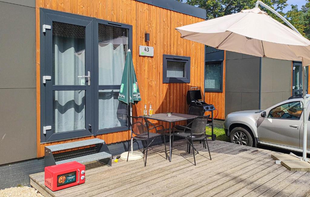 eine Terrasse mit einem Tisch, einem Sonnenschirm und einem Auto in der Unterkunft Tiny Haus 43 Am Brombachsee in Pleinfeld