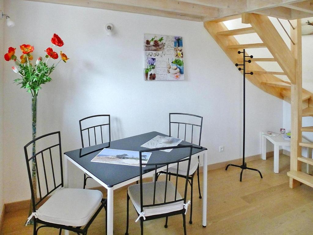 une table à manger avec des chaises et un vase de fleurs dans l'établissement Stone House in Plougasnou near Sandy Beach, cleaning included, à Plougasnou