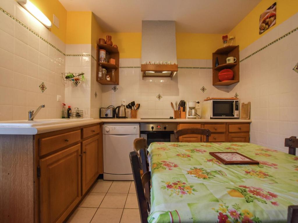 une cuisine avec une table et une cuisine aux murs jaunes dans l'établissement Holiday Home in Loubejac near Dordogne Lake, cleaning included, à Loubejac