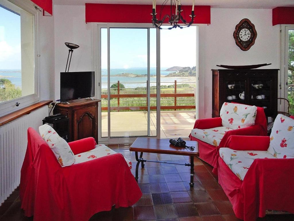 - un salon avec deux chaises rouges et une télévision dans l'établissement Holiday Home in Trébeurden with Sea View, cleaning included, à Trébeurden