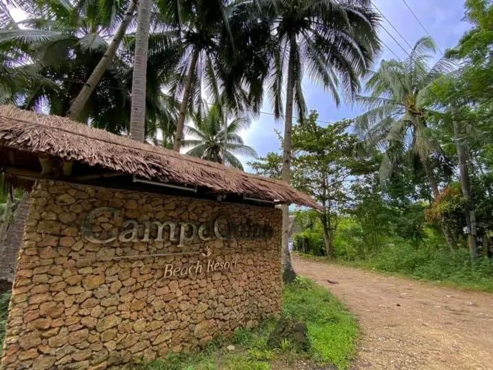 a sign for a resort with palm trees in the background at Campoquino Beach Resort in Sipalay