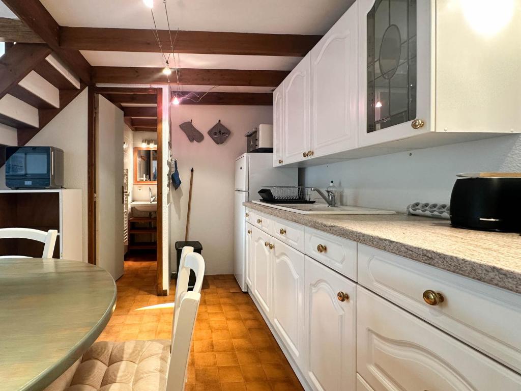- une cuisine avec des placards blancs et une table à manger dans l'établissement Maison 2 chambres, animaux admis, parking, La Palmyre - FR-1-705-99, aux Mathes