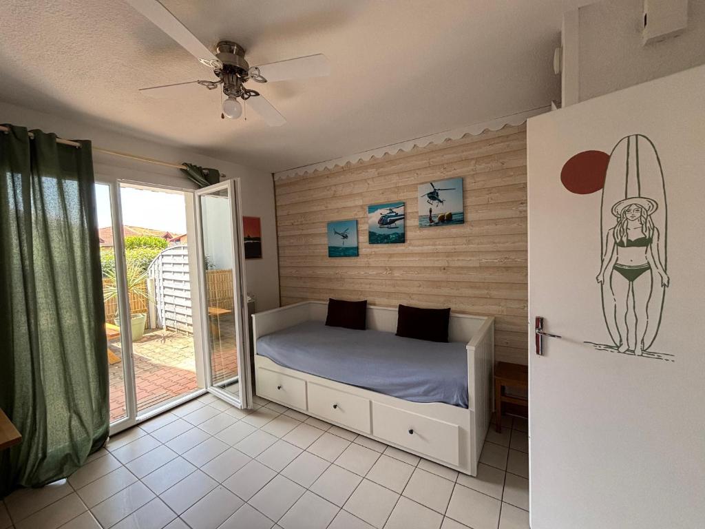 - une chambre avec un lit et une planche de surf sur le mur dans l'établissement Appartement à deux pas de la mer, Biscarrosse Plage - 4 pers. - Terrasse et Parking inclus - FR-1-319-447, à Biscarrosse