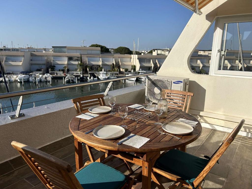 une table et des chaises en bois sur un balcon dans l'établissement Appartement 2 pièces, terrasse vue port, parking privé, clim, animaux admis - FR-1-250-313, au Grau-du-Roi