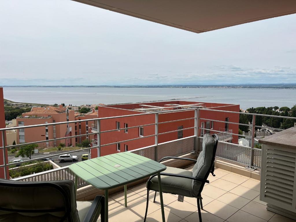 d'un balcon avec une table et des chaises et une vue sur un bâtiment. dans l'établissement Bel appartement climatisé avec piscine et garage à Sète - FR-1-338-624, à Sète