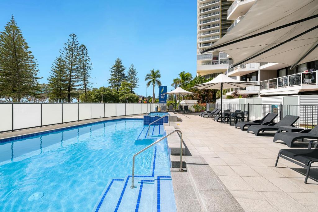 a swimming pool with chairs and a building at South Pacific Plaza - Official in Gold Coast