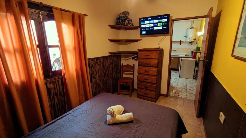 a small room with a bed and a kitchen at Benvinguts Casa y Apartamentos de 1 a 12 personas Pleno Centro Santa Rosa de Calamuchita in Santa Rosa de Calamuchita