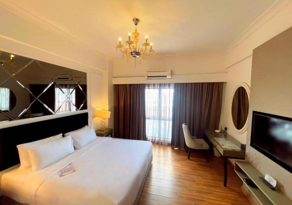 Una habitación de hotel con una cama, un escritorio y un televisor. en Imperial Heritage Hotel Melaka I City Centre I Free Wifi I Free Parking l Free Club Lounge Access, en Melaka
