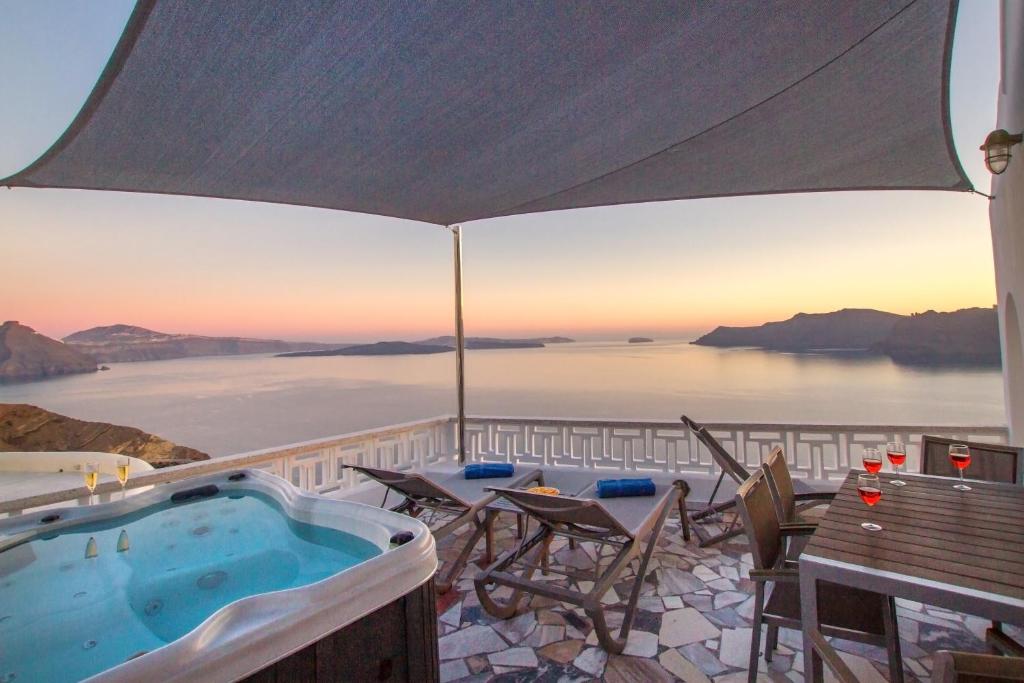 a hot tub on a patio with a view of the ocean at Compass Villa in Oia