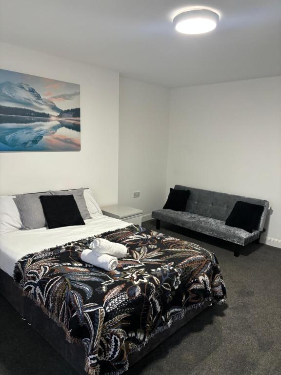 ein Schlafzimmer mit einem Bett und einer Couch in der Unterkunft Private Minimalist 2 Bedroom Apartment with Netflix in Ilkeston