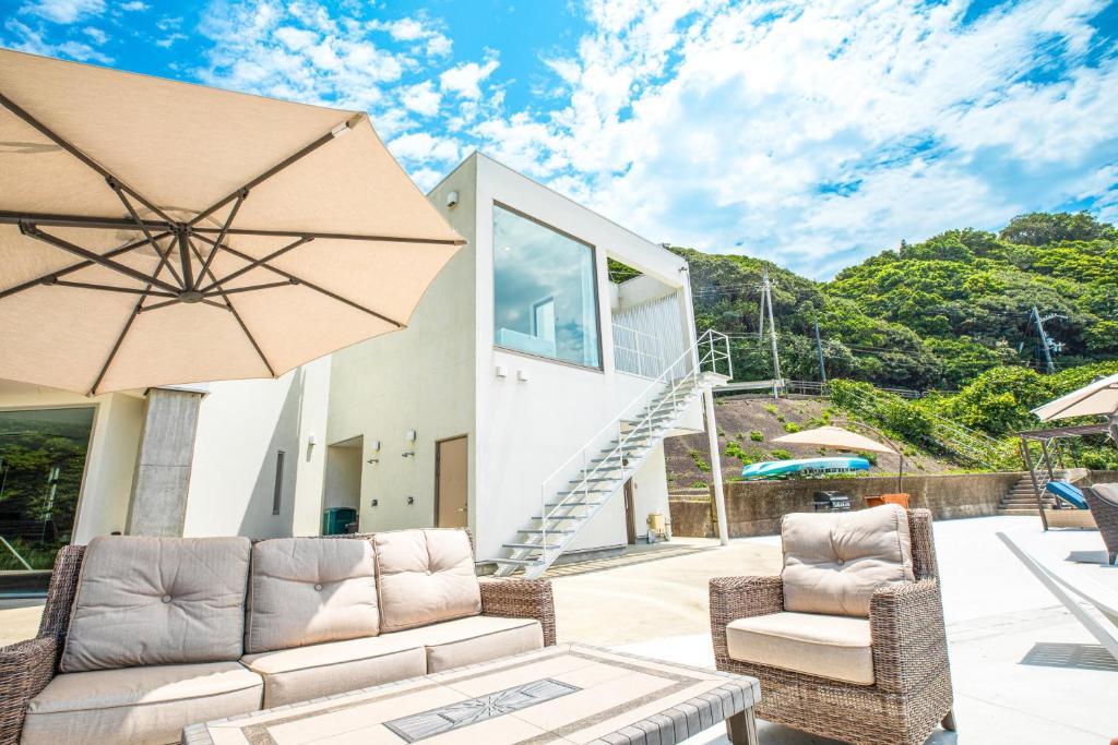 a patio with two chairs and a couch and an umbrella at 熊野古道ビーチテラス串本 in Wabuka