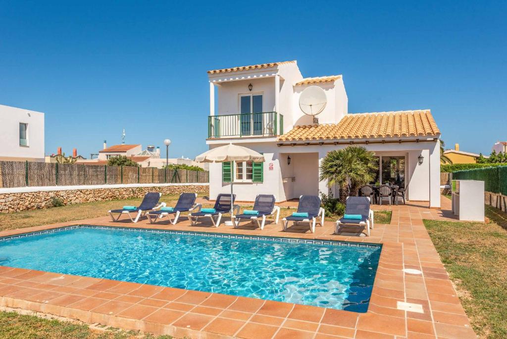a villa with a swimming pool in front of a house at Villa Aguasol in Cala en Forcat
