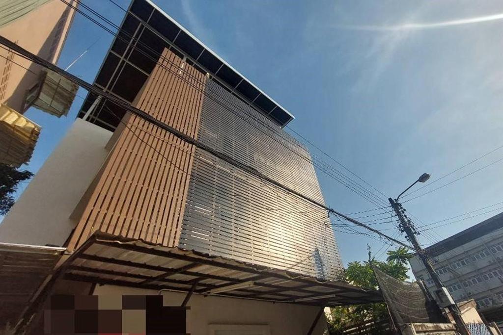 a tall building with a large metal grate on it at Sukhum Suvarnabhumi Airport Guest House in Ban Klong Plad Kriang