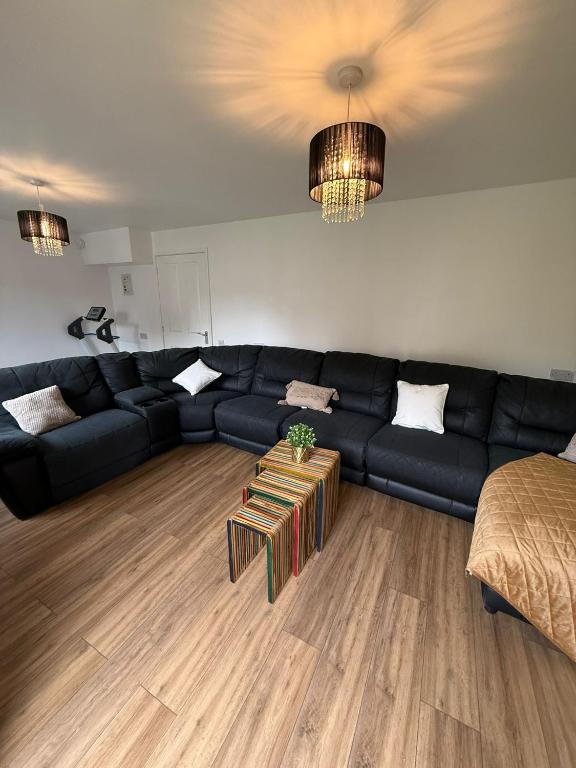 a living room with a black couch and a table at The Olive Villa in Manchester