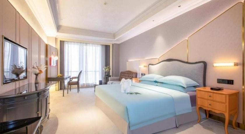 ein großes Schlafzimmer mit einem großen Bett und einem TV in der Unterkunft Zhejiang D.H Hotel in Haining