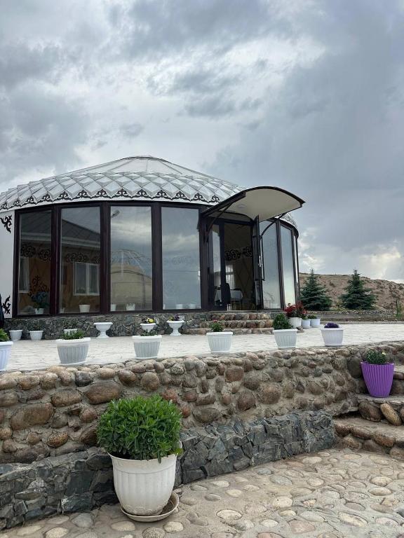 a stone wall with a gazebo with potted plants at Tasmal Yurt Camp in Tong