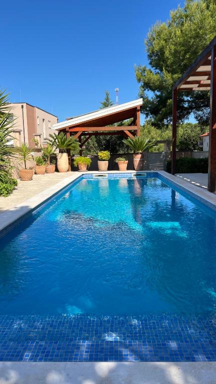 a large blue swimming pool with a pavilion at Pine Tree Villa in Pakoštane