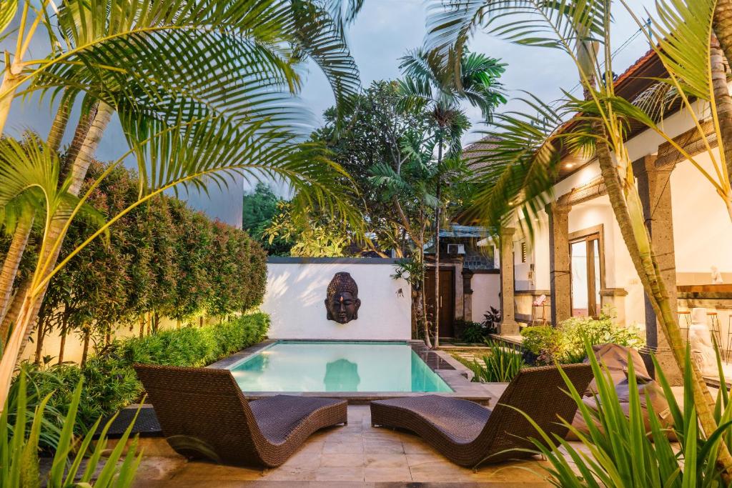 a courtyard with a swimming pool and palm trees at Villa Linda, Canggu, 3BR Pool, 3 min to FINNS in Canggu