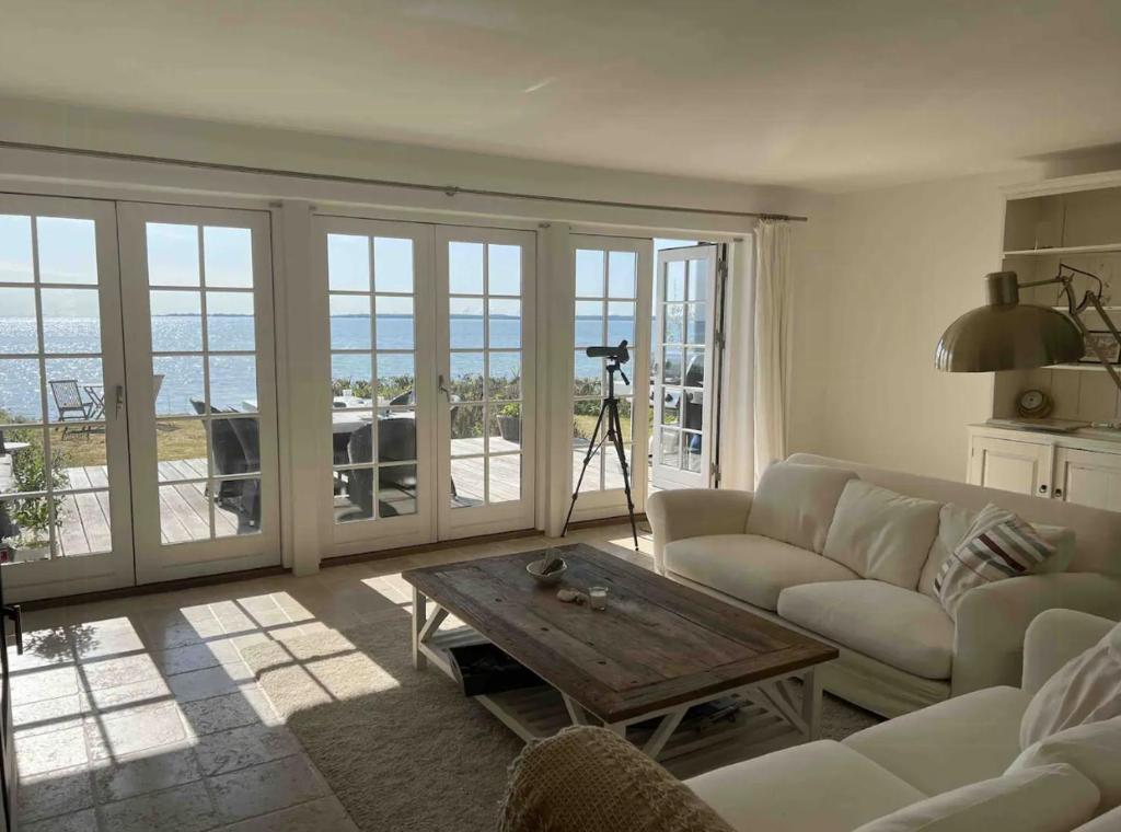 ein Wohnzimmer mit Sofa und Tisch in der Unterkunft Beachfront Summerhouse With Amazing View And Peace in Hesselager