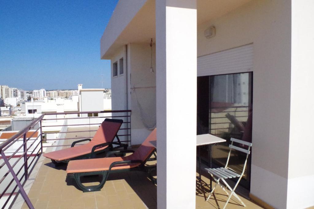 Un balcón con sillas y mesas en un edificio en BellaVita City Faro, en Faro