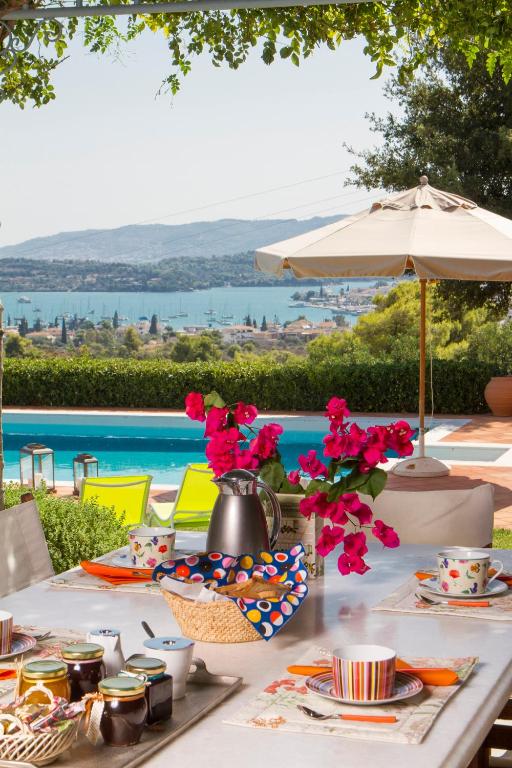 a table with food and flowers on it next to a pool at Villa Kate a Dreamy Summer Escape in Porto Heli