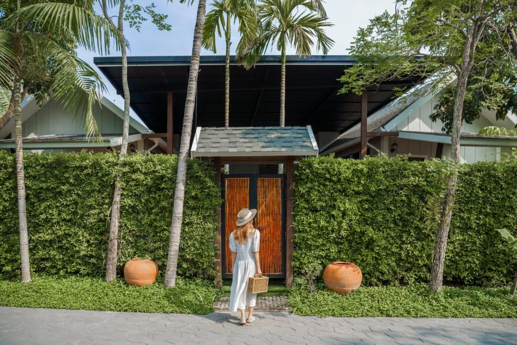 eine Frau mit Hut steht vor einer Tür in der Unterkunft IP Plus Pool Villa Pattaya in Jomtien Beach