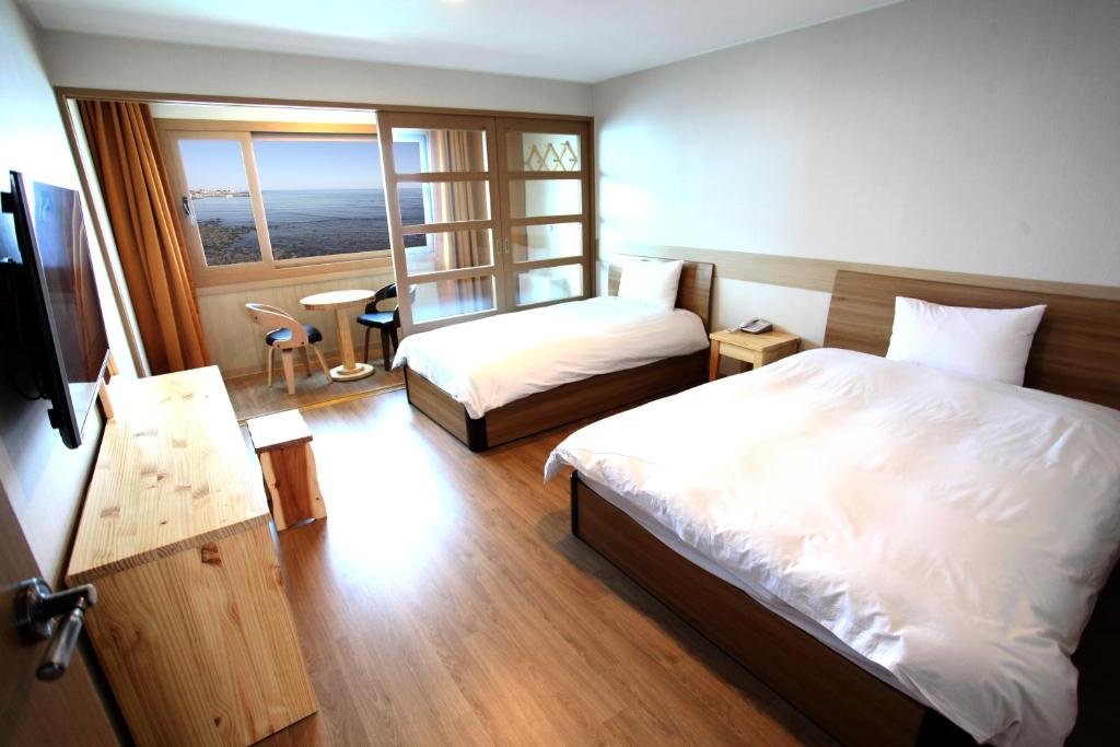 una camera d'albergo con due letti e una grande finestra di Fantastic Ocean View Sydney Hotel a Jeju