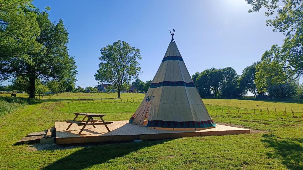 une table de pique-nique avec une tente sur un terrain dans l'établissement Au nid d'hirondelles, à La Celle-sous-Gouzon