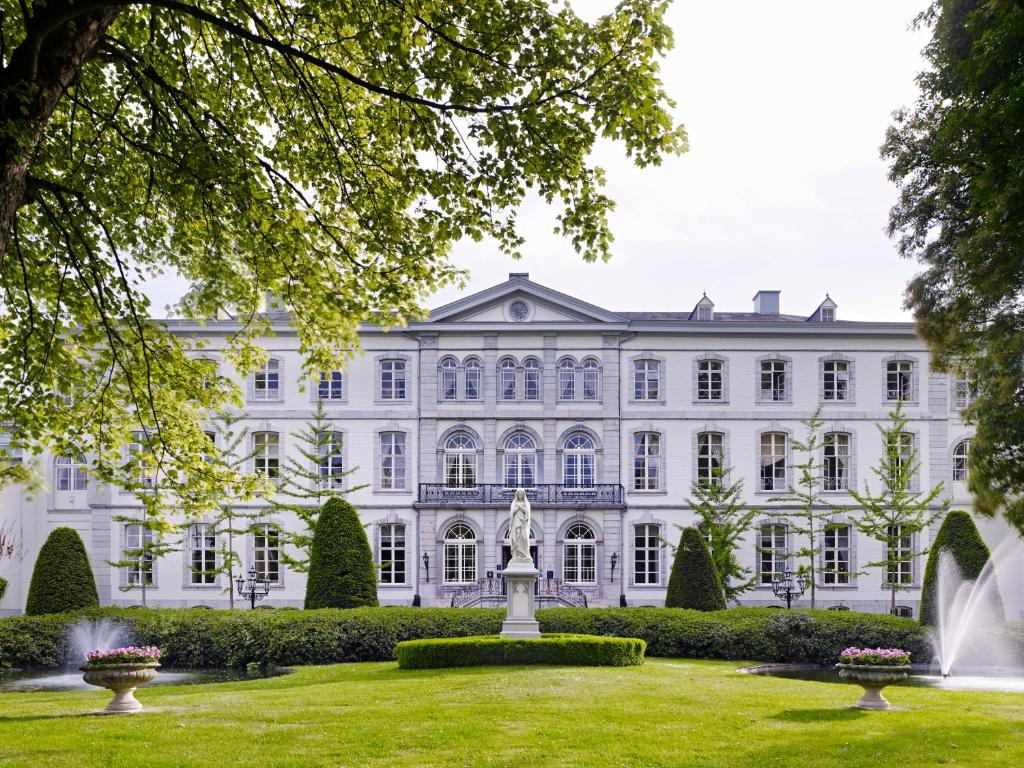 a large white building with a fountain in the yard at Hotel Kasteel Bloemendal in Vaals