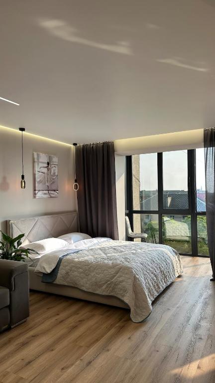 a bedroom with a large bed and a large window at luxury Apartmens na Duhnovicha , напроти Аквапарка "Карпатія" in Mukacheve