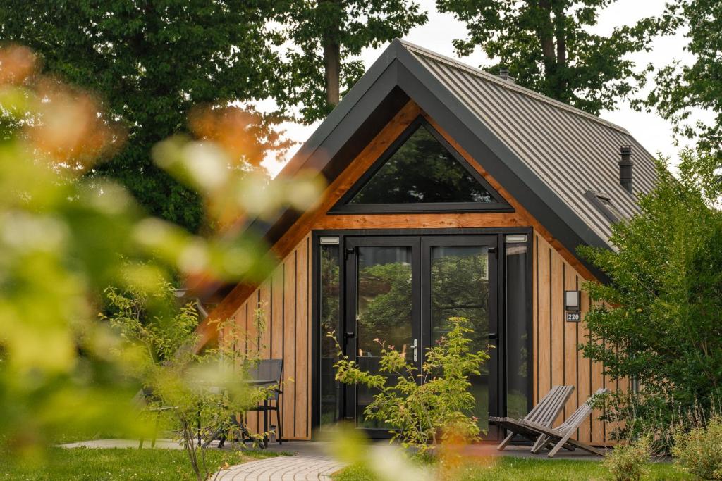a cabin with a glass door and a pitched roof at Wellness Lodges x De IJsvogel in Voorthuizen