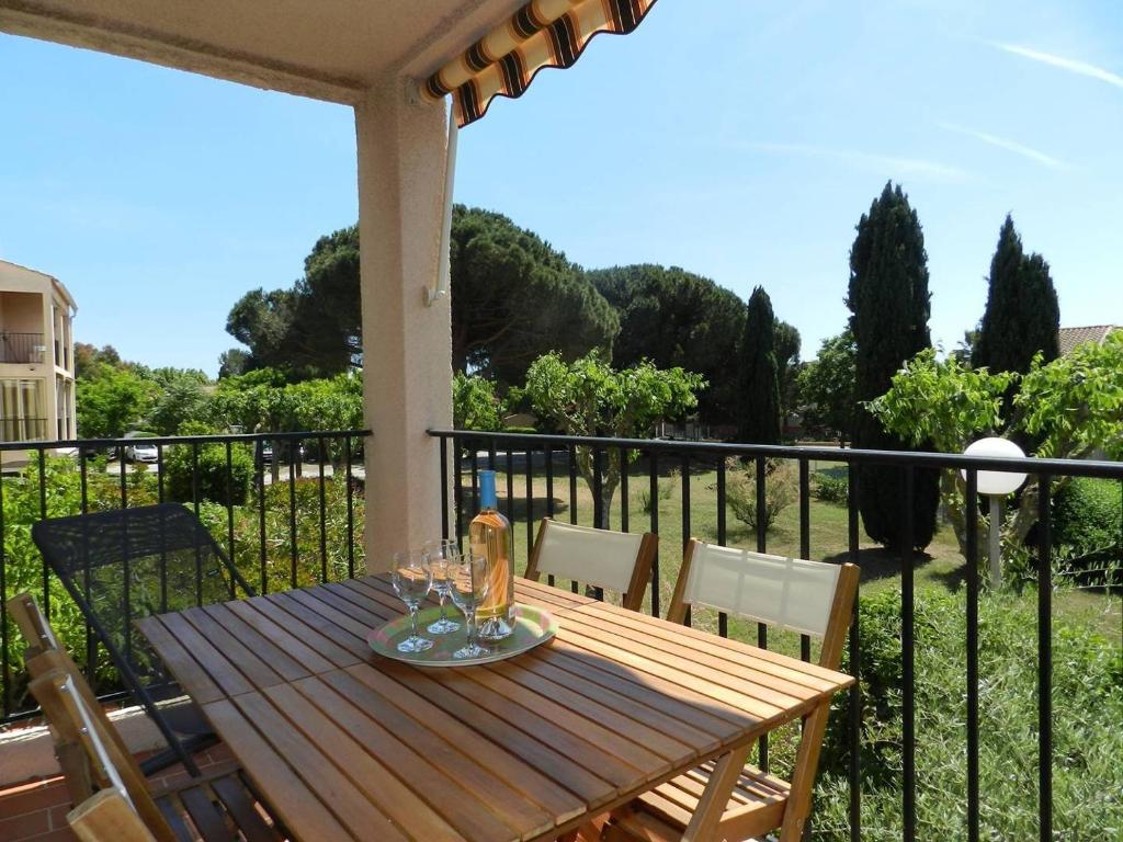 - une table en bois avec des verres à vin sur le balcon dans l'établissement Appartement 2 pièces 4 couchages LA LONDE LES MAURES LAL110-120, à La Londe-les-Maures
