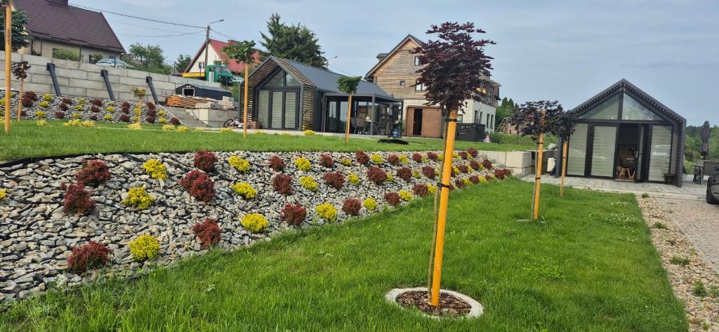 a row of flowers in a yard next to a stone wall at Domki nad zalewem in Gołdap