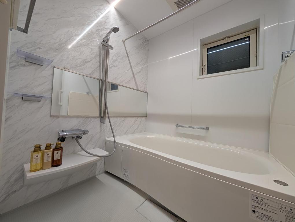 a white bathroom with a tub and a sink at 池袋本町302 in Tokyo