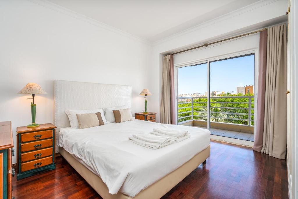 a bedroom with a white bed and a large window at Vilamoura Central 2 Bedroom Flat in Vilamoura