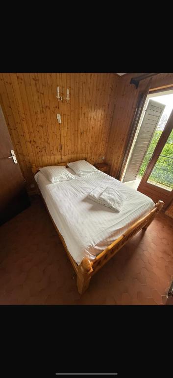 un grand lit dans une chambre avec une fenêtre dans l'établissement Choucas, à Thollon-les-Mémises