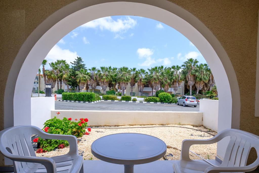 a patio with a table and chairs and palm trees at Pandream Hotel Apartments in Paphos