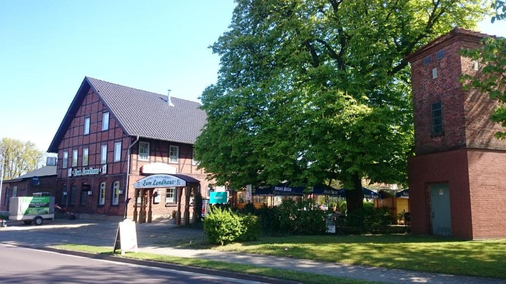 ein Gebäude an der Seite einer Straße mit einem Baum in der Unterkunft Zum Landhaus Dannenbüttel in Sassenburg