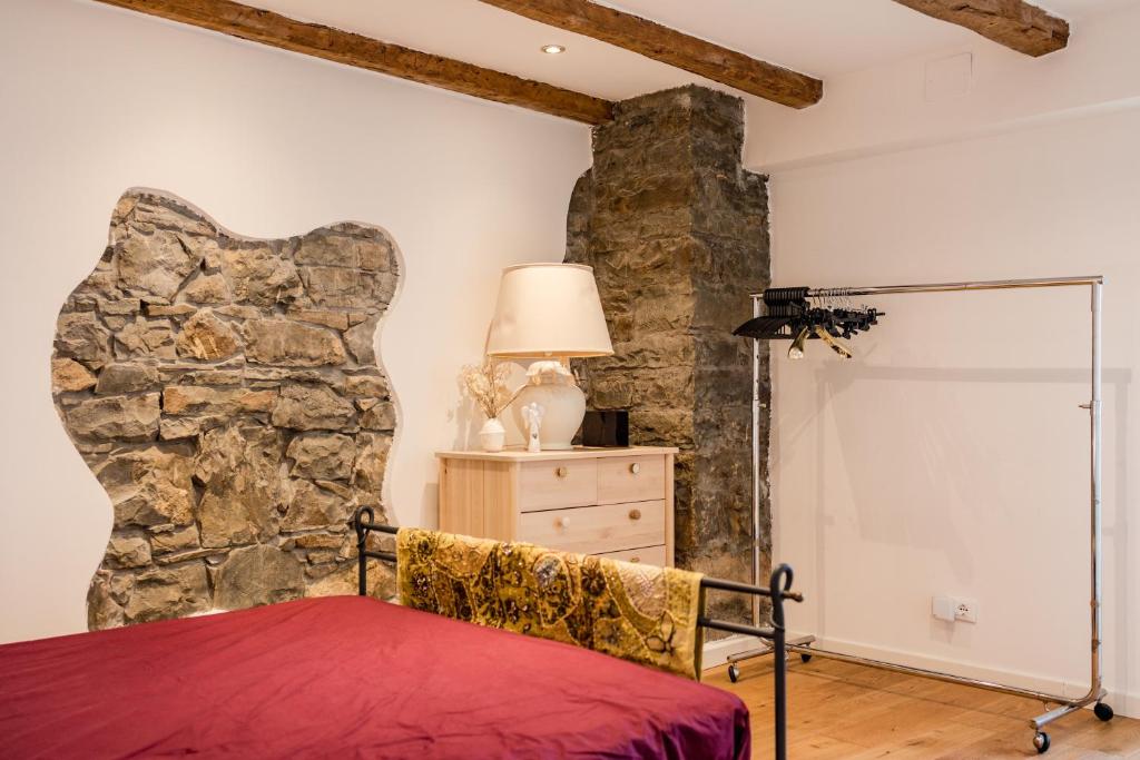 a bedroom with a stone wall next to a bed at Hurban Apartments La Casa dei Fiori in Trieste
