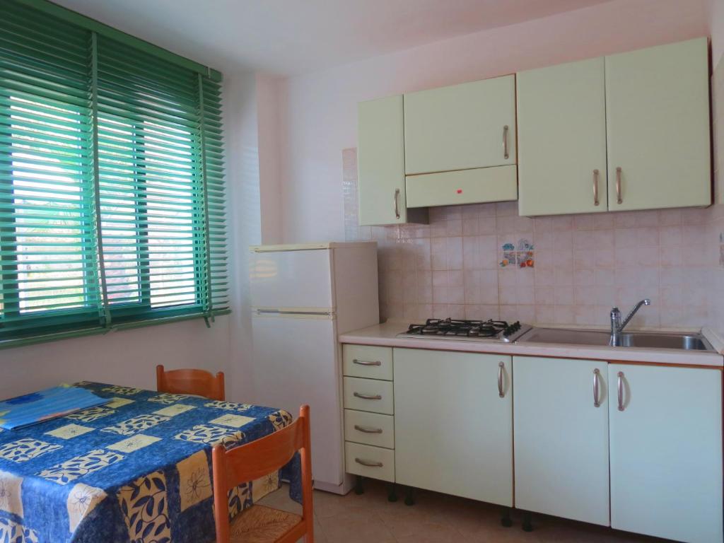 a kitchen with white cabinets and a sink and a table at Hotel Residence Villa Ascoli in Vieste